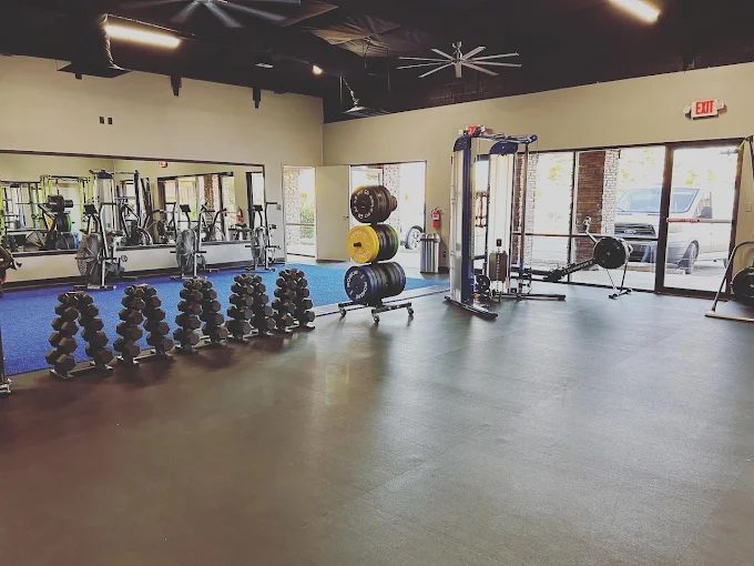 Dumbbell racks, bumper plates and a cable station on rubber flooring