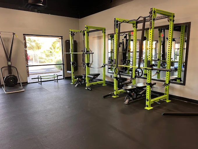 Power racks with benches and a rowing machine at the Desert Hybrid Health gym
